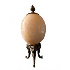 This is a vintage alabaster egg on a brass three-leg elephant head stand.